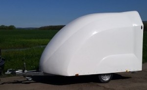 White enclosed motorbike trailer in front of a field