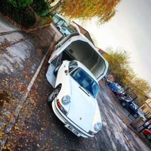 White Porsche 911 being unloaded from a white enclosed vehicle trailer