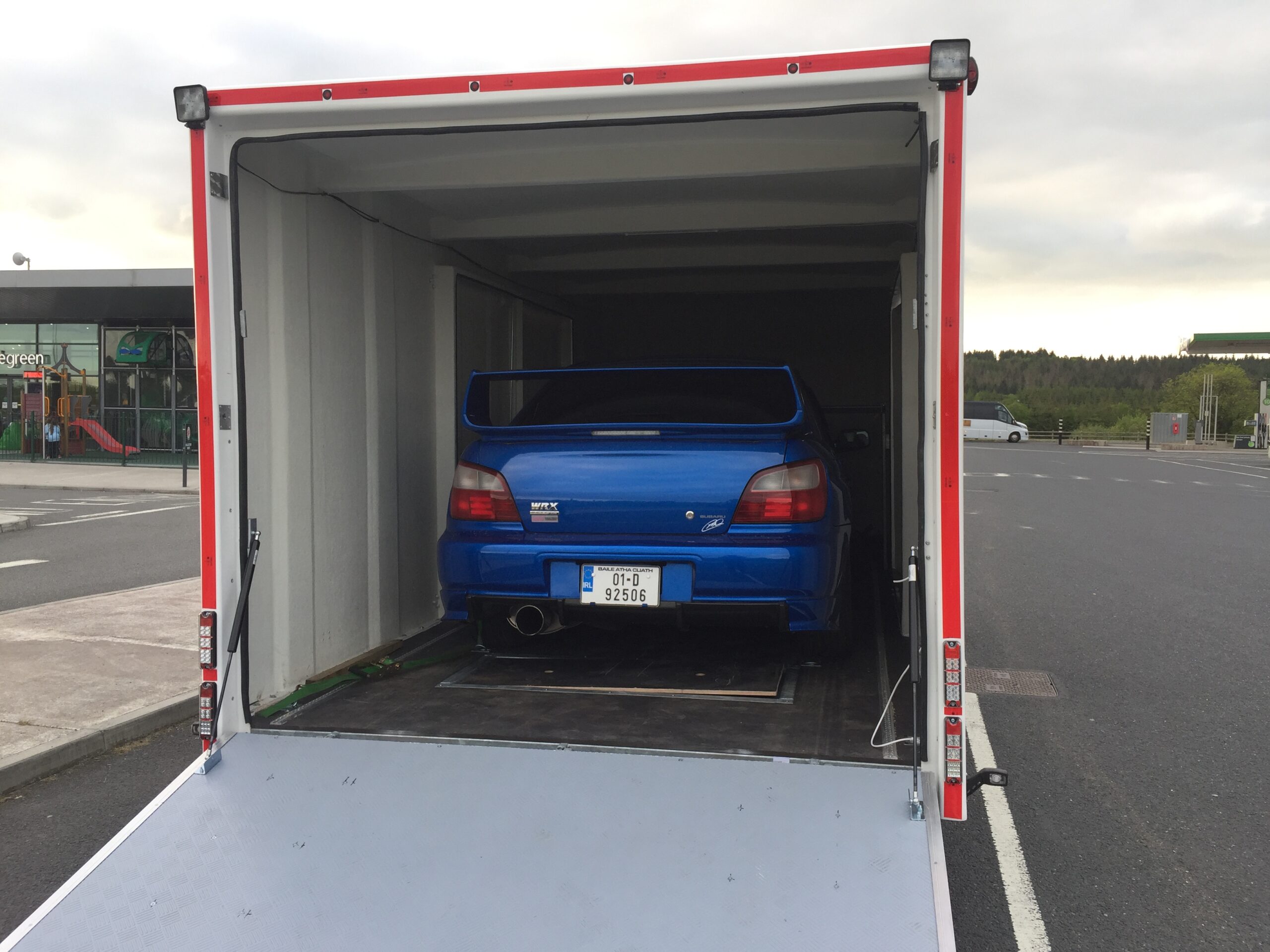 Blue Subaru inside a white enclosed vehicle trailer
