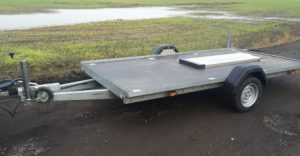 Flatbed trailer on the side of the road next to a field