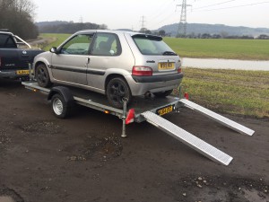 Silver Citroen Saxo on a grey flatbed trailer attached to a Nissan Navara