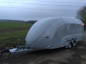 White vehicle trailer on the side of the road in front of a field
