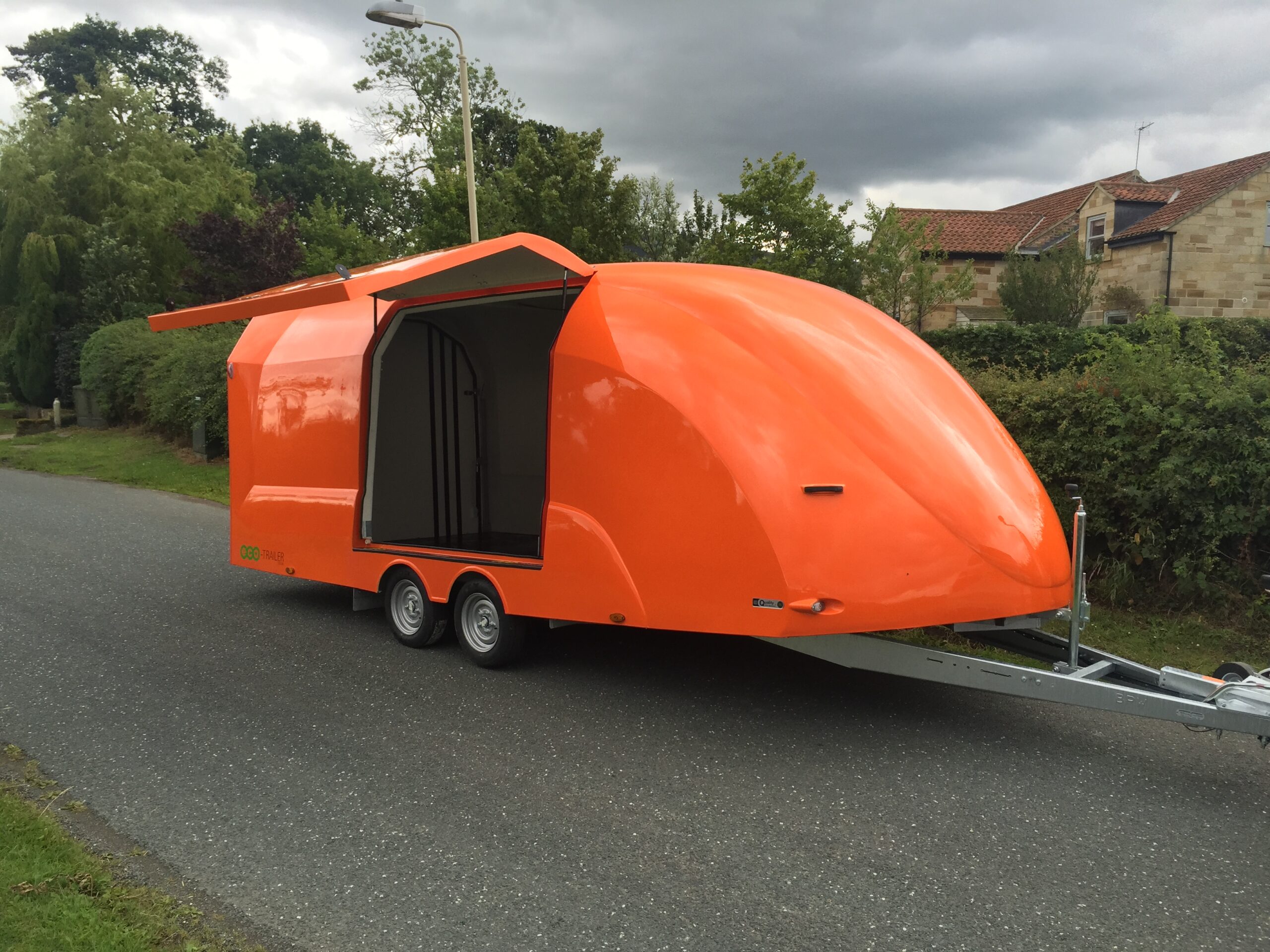 Orange enclosed vehicle trailer with the side hatch open