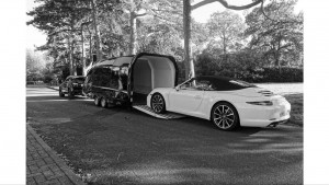 Black and white image of a Porsche 911 Carrera S in an enclosed vehicle trailer with the rear hatch down
