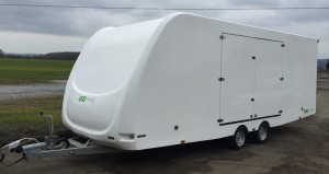 White enclosed vehicle trailer in front of a filed
