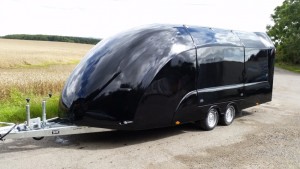 Black enclosed vehicle trailer in front of a field
