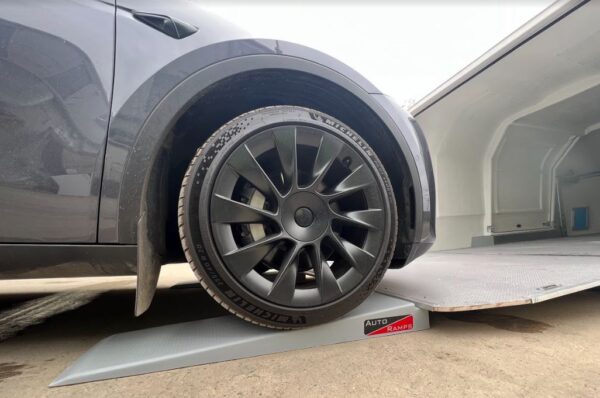 Car going up ramp into enclosed trailer with black wheel rim with Michelin tyres