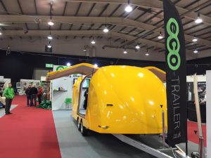 Yellow trailer at an expo with the doors open at a white stand