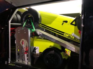 Two yellow caterhams in a black enclosed vehicle trailer with one on a ramp