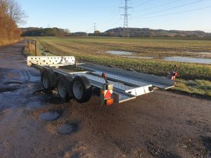Metal open trailer on a road next to a flooded field