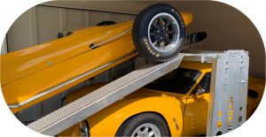 two yellow cars in a enclosed trailer with one on a ramp