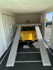 Yellow car under a car ramp inside a vehicle trailer