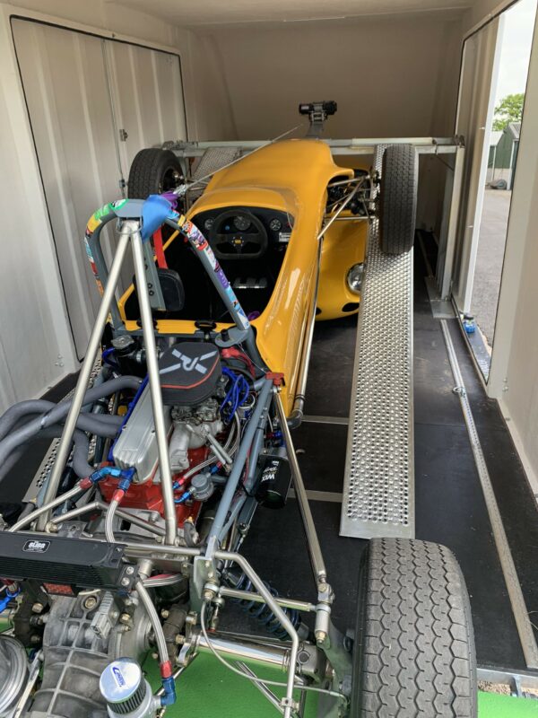 Yellow kit car on a silver ramp in a trailer