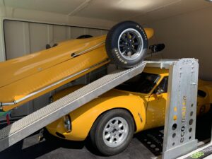 Two yellow vehicles in a trailer on a ramp
