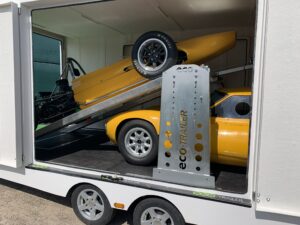 Two yellow vehicles in a white trailer on a ramp