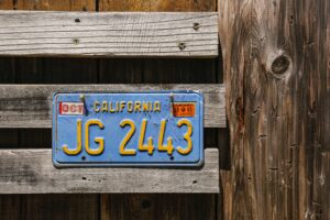 Blue car license plate with yellow text on a wooden fence